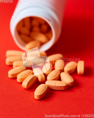 Image of Pills spilling out of pill bottle on red. Top view with copy space. 