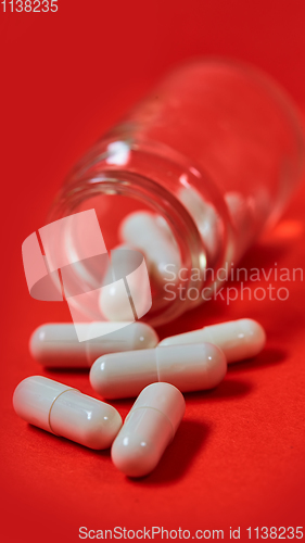 Image of Pills spilling out of pill bottle on red. Top view with copy space. 