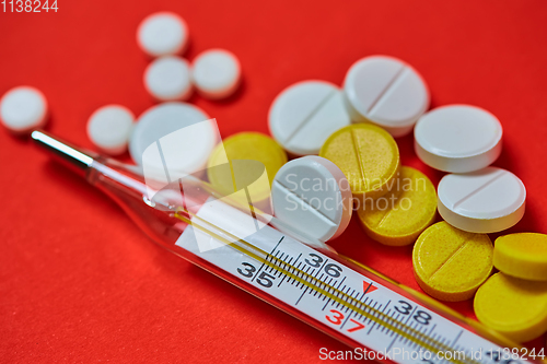 Image of Mercury thermometer and medical pills on background