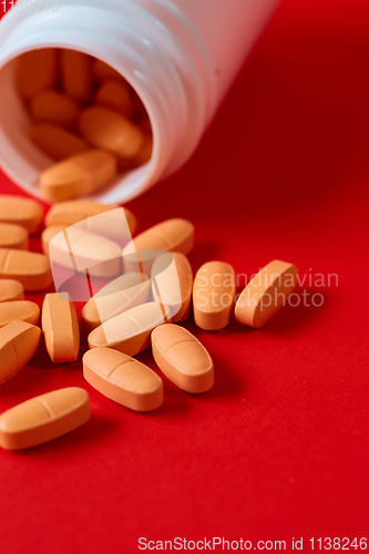 Image of Pills spilling out of pill bottle on red. Top view with copy space. 