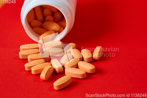 Image of Pills spilling out of pill bottle on red. Top view with copy space. 