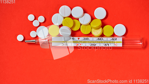 Image of Mercury thermometer and medical pills on background