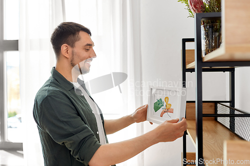 Image of man decorating home with picture in frame