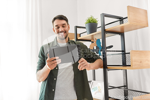 Image of happy smiling man with tablet pc at shelf at home