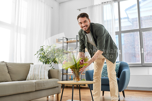 Image of man placing flowers on coffee table at home