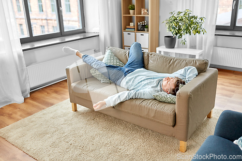 Image of young man sleeping on sofa at home