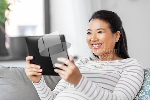 Image of happy pregnant asian woman with tablet pc at home