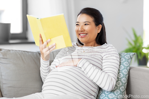 Image of happy pregnant woman reading book at home