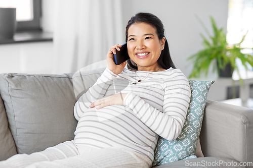 Image of happy pregnant woman calling on smartphone at home