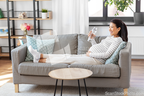 Image of pregnant woman with water in glass bottle at home