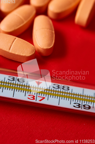 Image of Mercury thermometer and medical pills on background