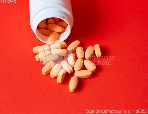 Image of Pills spilling out of pill bottle on red. Top view with copy space. 