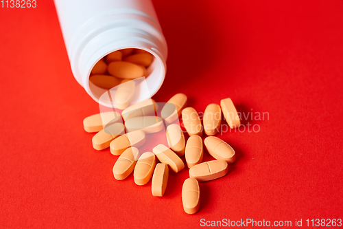 Image of Pills spilling out of pill bottle on red. Top view with copy space. 