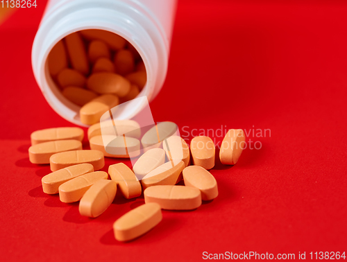 Image of Pills spilling out of pill bottle on red. Top view with copy space. 