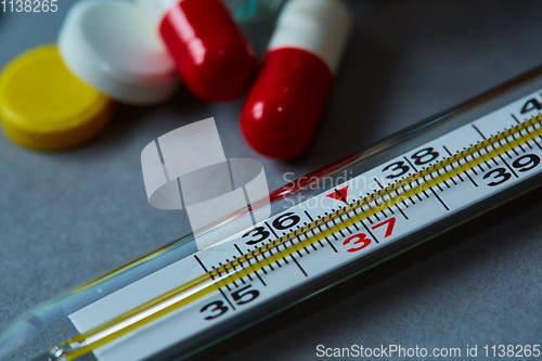 Image of Mercury thermometer and medical pills on background