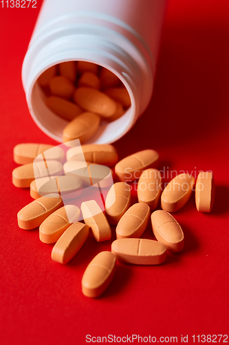 Image of Pills spilling out of pill bottle on red. Top view with copy space. 