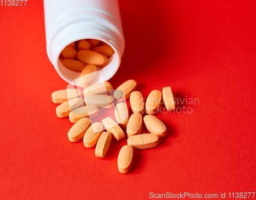 Image of Pills spilling out of pill bottle on red. Top view with copy space. 