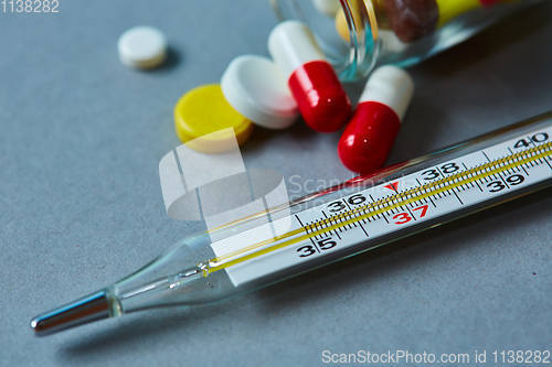 Image of Mercury thermometer and medical pills on background