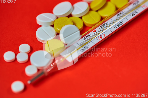 Image of Mercury thermometer and medical pills on background