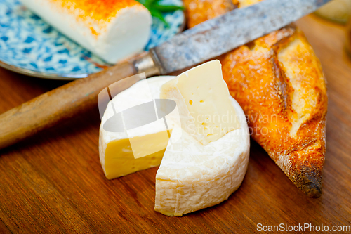 Image of French cheese and fresh  baguette on a wood cutter