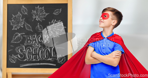 Image of boy in super hero costume over school blackboard