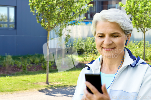 Image of sporty senior woman with earphones and smartphone