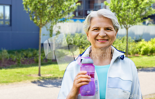 Image of sporty senior woman with bottle of water in city