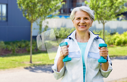 Image of senior woman with dumbbells exercising in city