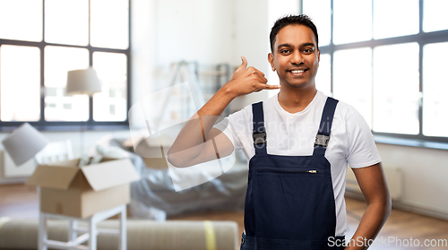 Image of happy worker making phone call gesture at new home