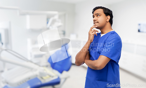 Image of thinking indian male doctor at dental office