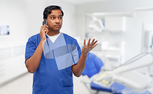 Image of indian doctor calling on phone at dental office