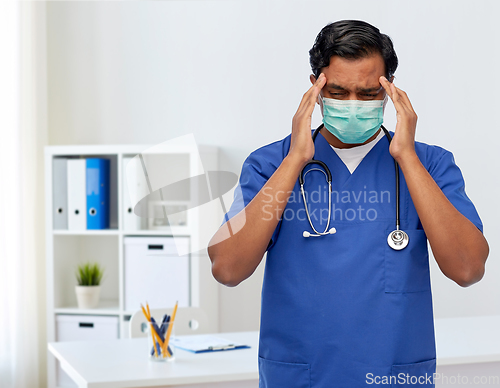 Image of stressed indian doctor in mask having headache