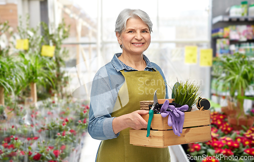 Image of senior woman with garden tools in gardening center