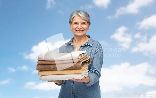 Image of smiling senior woman with clean fresh bath towels
