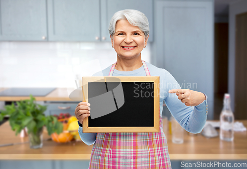 Image of smiling senior woman in apron with chalkboard