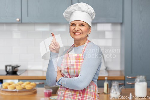 Image of smiling senior woman or chef pointing finger up