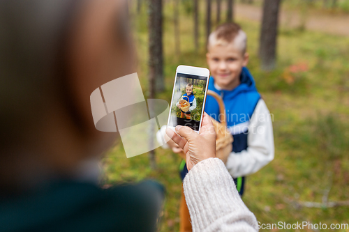 Image of grandmother photographing grandson with mushrooms