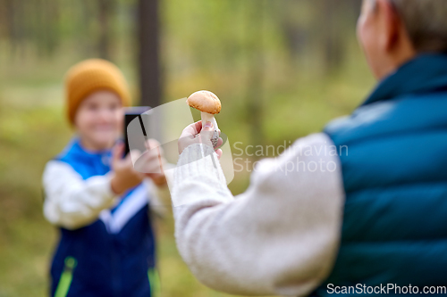 Image of grandson photographing grandmother with mushroom
