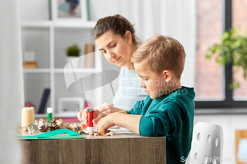 Image of mother and son making pictures of autumn leaves