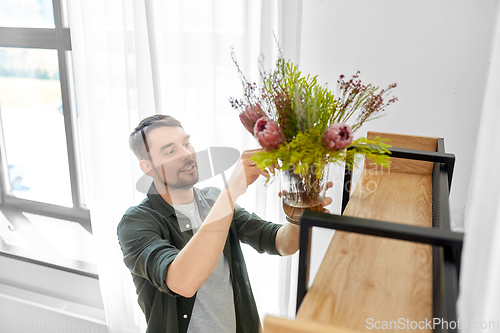 Image of man decorating home with flowers in vase