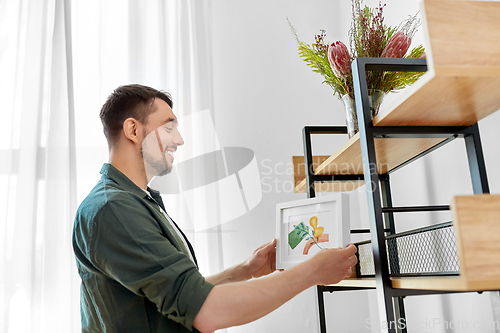 Image of man decorating home with picture in frame