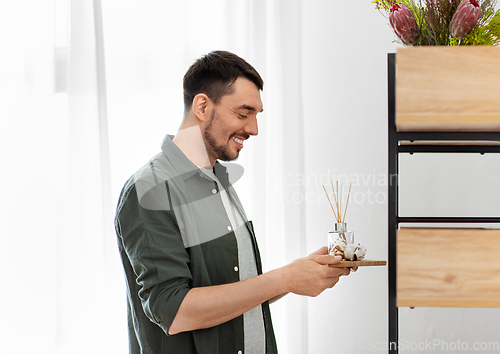 Image of man placing aroma reed diffuser to shelf home