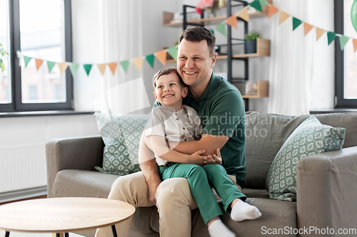 Image of happy father and little son at home birthday party