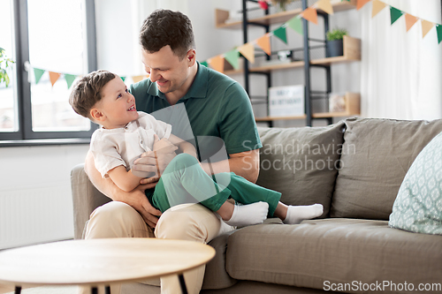 Image of happy father and little son at home birthday party