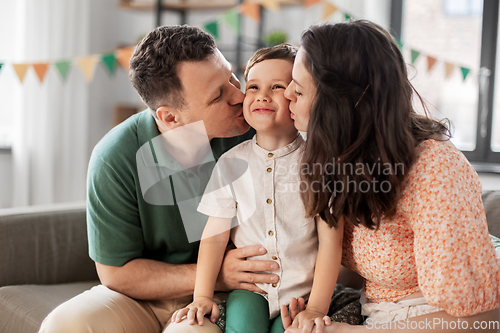 Image of happy parents kissing little son at birthday party