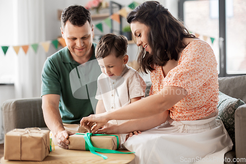 Image of happy family opening birthday presents at home