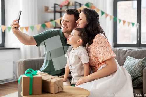 Image of happy family taking selfie on birthday at home
