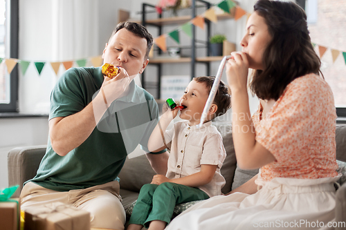 Image of happy family with gifts and party blowers at home