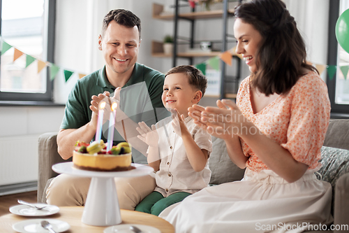 Image of happy family with birthday cake at home