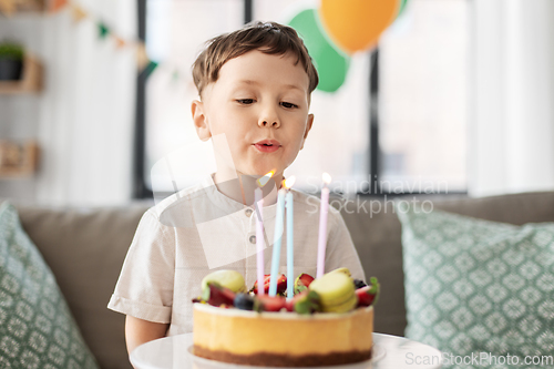 Image of happy little boy blowing candles on birthday cake